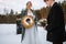 The groom looks in the mirror held by the bride. The bride is wearing a fabulous protective mask. Behind the piano