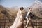 Groom in modern suit and bride in charming pink dress pose on the terasse with great mountain view in Georgia