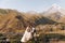 Groom in modern suit and bride in charming pink dress pose on the terasse with great mountain view in Georgia