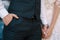 Groom in a navy suit holding his hand in his pocket. Bride is holding his other hand with hers. Fine-art wedding photo