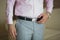 The groom in a pink shirt and grey trousers.
