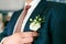 Groom is pinning a boutonniere to a suit. Wedding preparation