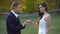 Groom putting beautiful ring on finger of his bride and kisses her hand in sunny rays at autumn park