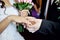 Groom putting on wedding ceremony for bride gold ring on the finger