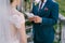 Groom reads an oath from a sheet of paper to bride in a white dress. Close-up