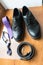 The groom`s and a dogâ€™s wedding accessories. Lilac neck tie and a black leather belt and black shoes on a wooden background.