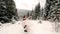 Groom spinning happy bride holding and spinning her in his hands in snow weather fir tree spruce forest during snowfall