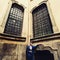 Groom stands in the angle under big old windows