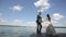 Groom stands near bride and jumping. Lovely wedding couple stands near lake. Slow motion