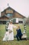 The groom stands on one knee in front of his bride next to dog and a wedding arch