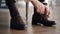 Groom ties laces close up against background of timber floor.