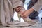 the groom wears wedding shoes on the bride. Young husband helping bride to wear dress sandals