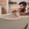 Grooming beard. Bearded man with beard with mirror in hand. Morning hygiene. Skincare in home bathroom.