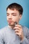 Grooming and self care. Portrait of concentrated focused brunette man shaving with trimmer. isolated on blue background