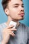 Grooming and skin care. Portrait of attentive focused brunette man removing facial hair. isolated on blue background