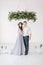 Groomsman and bridesmaid dressed in grey blue dress standing in white room with wedding decorations