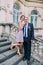 Groomsman posing with cute bridesmaid on the stairs of classical austrian building