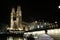 Grossmunster protestant church illuminated at night in Zurich  photographed from across the Limmat river with the old bridge