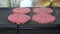 Ground beef patties simmering on an electric grill, slow motion