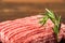 Ground chicken with a sprig of rosemary on a wooden plate on a textural table. Turkey mince raw close-up and copy space