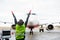 Ground Crew Signaling To Airplane On Runway