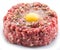 Ground cutlet or raw hamburger with quail egg yolk and seasonings on white background. Close-up