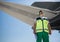 Ground handling crew member standing near giant airplane wing