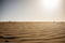 Ground level view of desert sand at sunset with sun hitting hard from above giving a sense warm and hot wth nobody