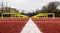 Ground level view of yellow mini hurdles set up in lanes on a track for speed training