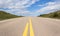 A ground shot of paved highway going up hill into the distance