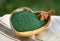 Ground Spirulina in bowl on textile background, top view on heart shape dish with superfood