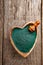 Ground Spirulina in heart shape bowl on wood background, top view