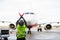 Ground Worker Signaling To Airplane On Runway