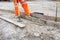 Groundworker making shutter for concrete to form a base for kerb using scaffold boards and steel road pins