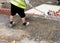 Groundworker placing semi-dry concrete around concrete edging kerb during footpath construction