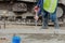 Groundworker placing wet concrete inside formwork during roadworks