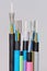 Group of 7 different fiber optic cable ends with stripped jacket and exposed colored fibers