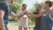 Group of active mature friends in park stacking hands after workout