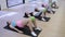 Group of active people engaged in Pilates in the gym performs a lying twisting exercise, clomped a miniball between