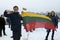 Group of activists keeping Lithuanian flag and poster with writing Lithuania singing the anthem. Celebration of 100