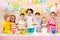 Group of adorable kids stand around festive table at birthday party