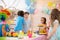 Group of adorable kids stand around festive table at birthday party