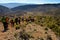 group of adult people with colorful backpack trekking on a path of sand and stones walking down a mountain with a amazing