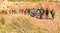 group of adult people with colorful backpack trekking on a path of sand and stones walking to mountain with a amazing landscape on