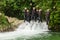 Group Of Adult People Jumping Into Small Waterfall