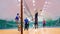 Group of adult people plays volleyball in gym.