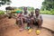 Group of African siblings sitting on the side of the road, they are poor and dressed in worn