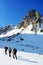 Group of alpinists trekking on a snowy mountain path in a wonderful sunny day.