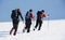 Group of alpinists trekking on a snowy mountain path in a wonderful sunny day.