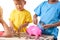 Group of asian children are helping putting coins into piggy bank on white background. Education concepts